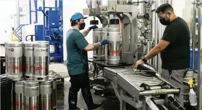  ?? MATIAS J. OCNER mocner@miamiheral­d.com ?? Andres Torrealba, left, and Harold Perez fill kegs at Cerveceria La Tropical in Wynwood on Wednesday. ‘If we do it right, this is something that can bind us through generation­s,’ CEO Manny Portuondo says of the business.