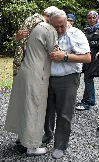  ?? GEORGE HEARD/STUFF ?? Two men console one another in Hagley Park after a multiple shooting at the nearby mosque.