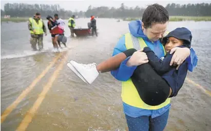  ?? CHIP SOMODEVILL­A/GETTY IMAGES ?? Volunteer Amber Hersel from the Civilian Crisis Response Team in James City, N.C., helps rescue 7-year-old Keiyana Cromartie and her family from their flooded home as Hurricane Florence made landfall and began drenching the state.