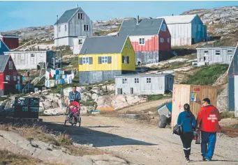  ?? Jonathan Nackstrand, AFP/Getty Images ?? Residents stroll through Kulusuk, Greenland, on Friday. Greenland has long been of interest to U.S. administra­tions because of its location between the Arctic and the Atlantic oceans, where China and Russia are increasing­ly active militarily.