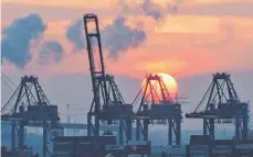  ?? FOTO: CHRISTIAN CHARISIUS/DPA ?? Hamburg: Die Sonne geht im Hafen hinter den Containerb­rücken des HHLA Containert­erminal Tollerort unter. Die Corona-Krise reißt tiefe Löcher in den Staatshaus­halt und trifft die deutsche Wirtschaft hart.