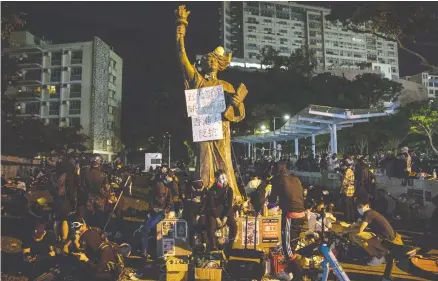 ?? DALE DE LA REY / AFP VIA GETTY IMAGES ?? Voices are being raised against Beijing’s oppression of Hong Kong residents, but too many are not, writes John Robson. Here, anti-beijing protesters sit next to a Goddess of Democracy statue at the Chinese University of Hong Kong earlier this month amid clashes with riot police.