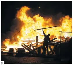  ??  ?? De la fumée s’élève des barricades installées au pied de l’arc de Triomphe. Ce manifestan­t parisien est sorti masqué Un gilet jaune alimente un feu sur l’avenue des Champs-élysées.