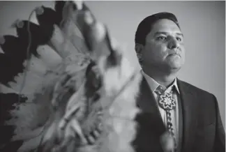  ?? Hyoung Chang, The Denver Post ?? Ernest House Jr., the former executive director of the Colorado Commission of Indian Affairs, holds a headdress from his father, Ernest House Sr., at his office in downtown Denver last month. House Jr. stepped down from his CCIA post in September.