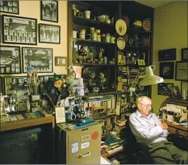  ?? Genaro Molina Los Angeles Times ?? FORMER UCLA coach John Wooden, sitting in his den stacked with memorabili­a at his home in Encino in 2006, never made more than $32,500 a year at UCLA.