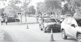  ??  ?? Dozens of families line up at San Isidro Catholic Church in Pompano Beach at a drive-thru distributi­on of household goods and otherbasic essentials.