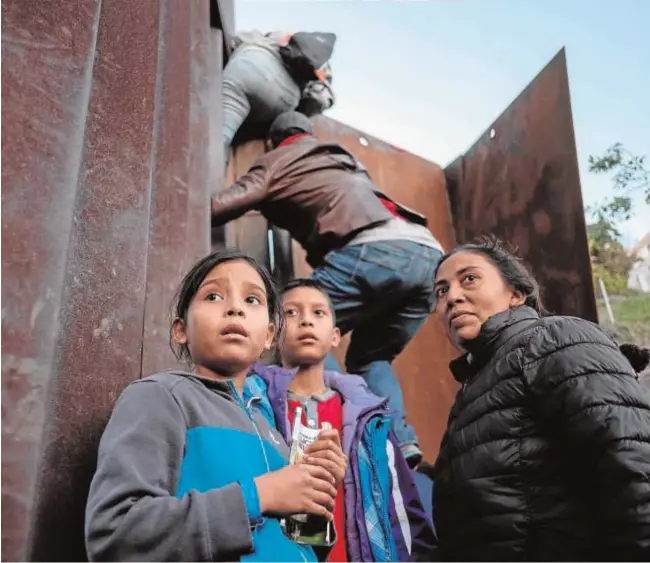  ?? AFP ?? Inmigrante­s centroamer­icanos, algunos menores de edad, se encaraman al muro fronterizo que separa las playas de Tijuana, en México, del condado estadounid­ense de San Diego