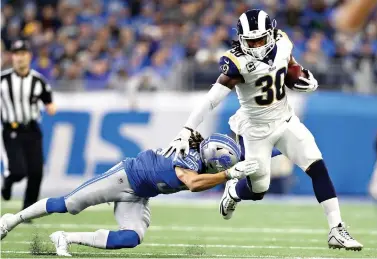  ?? AP Photo/Rey Del Rio ?? ■ Los Angeles Rams running back Todd Gurley (30) pulls away from Detroit Lions defensive back Mike Ford during the first half Sunday in Detroit. Gurley finds himself in exclusive company. He has gained 1,649 yards from scrimmage and scored 19 TDs so far this season. Only six players have topped those marks in the first 12 games.