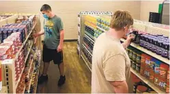  ?? ANTHONY LOVE VIA AP ?? Student Hunter Weertman, 16, (left) stocks shelves and takes inventory while working at the student-led free grocery store at Linda Tutt High School.