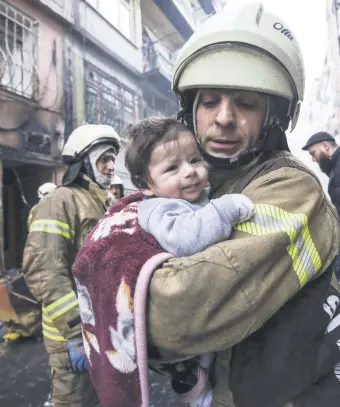  ??  ?? A firefighte­r saves a baby from house fire due to a natural gas explosion, Fatih, Istanbul.