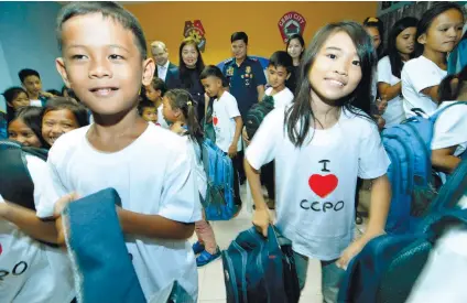  ?? SUNSTAR FOTO/ AMPER CAMPAÑA ?? SANTA COPS. These children are all smiles after receiving bags and school supplies during an early Christmas party organized for them by the Cebu City Police Office.