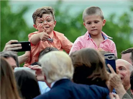  ?? PHOTO: REUTERS ?? A boy gives a thumbs-up to US President Donald Trump as he greets members of Congress and their families at a congressio­nal picnic at the White House yesterday.