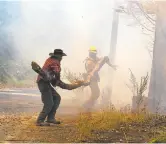  ??  ?? Matthew Borek, left, helps a firefighte­r clear a fallen branch from a road near his home as the battle continues against the Soberanes fire Wednesday.