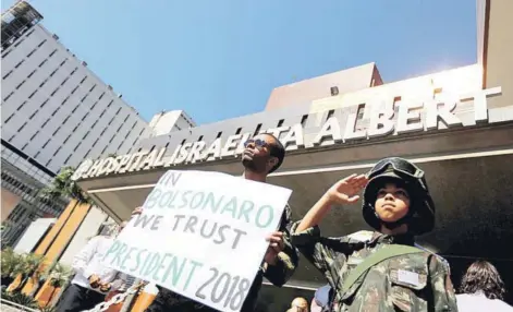  ??  ?? ► Partidario­s de Jair Bolsonaro exhiben carteles en su apoyo fuera del hospital donde está internado.