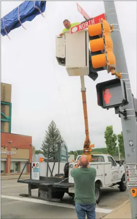  ?? ?? Jose Rodriguez from the Fitchburg Department of Public Works throws down the rope attached to the tarp covering one of the two bright red signs designatin­g Gerry Martel Square at the intersecti­on of North and Main streets to DPW signs shop supervisor Michael East prior to the dedication ceremony on Wednesday.