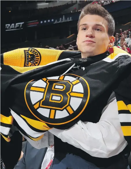  ?? GETTY IMAGES ?? Tecumseh’s Jack Studnicka puts on a Boston Bruins jersey after the team selected him 53rd overall at the 2017 NHL Draft on Saturday at the United Center in Chicago. “I’ve been dreaming about being drafted to the NHL since I can’t remember,” the...