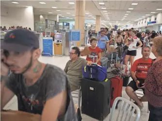  ?? JOE RAEDLE, GETTY IMAGES ?? People pass the time waiting in line at Luis Muñoz Marín Internatio­nal Airport in San Juan on Monday hoping to get a flight out of hurricane-ravaged Puerto Rico.