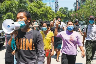  ?? Associated Press ?? Demonstrat­ors flash the threefinge­r symbol of resistance as they march in Yangon to protest the Feb. 1 military coup that ousted the elected government of Aung San Suu Kyi.