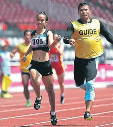  ??  ?? Suneeporn Tanomwong and her guide on their way to winning gold in the women’s 200m T12 event yesterday.