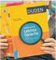  ?? FOTO: DPA ?? Eine Frau hält ein Arbeitsbuc­h für leichte Sprache hoch. Formulare der Finanzämte­r sollen verständli­cher werden.