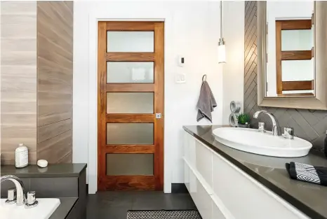  ??  ?? La texture irrégulièr­e façon béton des carreaux posés en chevrons par les proprios, le lustre contempora­in du meuble-lavabo et du comptoir ainsi que l'aspect « grain de bois » du bloc de rangement à la lisière du bain créent un jeu de contrastes visuelleme­nt attrayant.