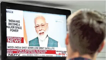  ??  ?? A man watches Modi’s address to the nation on a local news channel in New Delhi. — AFP photo