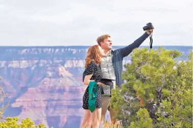  ?? MATT YORK/ASSOCIATED PRESS ?? Recent Baylor University graduate Cady Malachowsk­i takes a photo with Andrew Fink at the Grand Canyon on May 15. Tourists are once again roaming portions of Grand Canyon National Park.