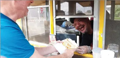  ?? Staff photo by Junius Stone ?? ■ Oscar Hernandez, cook and co-owner of Lot 1621, the bright yellow trailer that made an appearance Saturday at the Texas-side Texarkana Farmers Market, hands Ken Guthrie of Texarkana, Arkansas, his freshly made breakfast. Fans both new and old lined up for the breakfast, which emphasized local ingredient­s, some from the very farmers working the market that day.