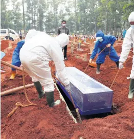  ?? AP ?? Workers in protective gear lower a coffin of a COVID-19 victim to a grave for burial at the Cipenjo Cemetery in Bogor, West Java, Indonesia yesterday.