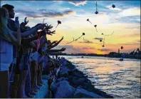  ?? RICHARD GRAULICH / THE PALM BEACH POST ?? Friends and supporters throw flowers into the ocean during the Light the Coast event marking the two-year anniversar­y for missing teen boaters Austin Stephanos and Perry Cohen at the Jupiter Inlet on July 24, 2017.