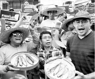  ??  ?? Members of Akbayan activist group display fish as they chant slogans during a rally to protest what they say is harassment of Filipino fishermen at the Scarboroug­h Shoal in the disputed south China sea, in Makati, Metro Manila.