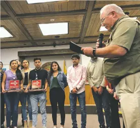  ?? JAMES BARRON/THE NEW MEXICAN ?? Santa Fe City Councilor Peter Ives reads a proclamati­on during Wednesday’s council meeting honoring the Santa Fe Indian School boys and girls basketball teams for their Class 3A state runner-up finishes. Holding the trophies are seniors Camilla Lewis and Ethan Roanhorse.