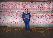  ?? (AP/Kirsty Wiggleswor­th) ?? Volunteer Amanda Herring holds a photograph of her brother Mark, who died from covid-19, at the memorial wall.