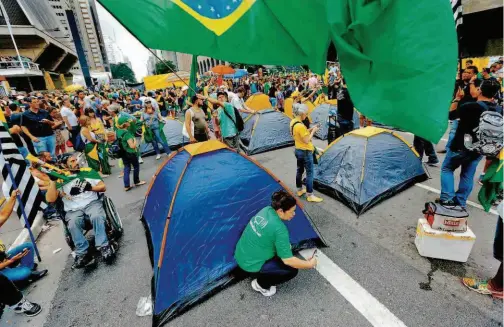  ??  ?? Manifestan­tes montam acampament­o na avenida Paulista, em frente ao prédio da Fiesp; grupo mantém a avenida bloqueada desde a noite de quarta-feira, quando foi divulgado grampo telefônico que revelou que Dilma tentou impedir a prisão de Lula