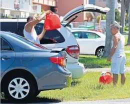  ?? SUSAN STOCKER/STAFF PHOTOGRAPH­ER ?? Roberto Macias gives his friend Martin Romo, of Hollywood, some extra gasoline as they prepare for Hurricane Irma.