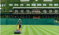  ?? (AFP) ?? A ground staff tends to the grass on Court 6 at the All England Lawn Tennis Club in west London yesterday.