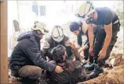  ?? Mohamad Abazeed AFP/Getty Images ?? MEMBERS of the Syria Civil Defense, known as the “White Helmets,” help a victim in Dara, Syria.