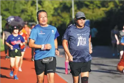  ?? CHEN ZEBING / CHINA DAILY ?? A volunteer guide helps a visually impaired runner during a training session at the Olympic Green in Beijing on Sept 8. The guide is part of a group that has more than 1,000 visually impaired runners and over 600 people willing to help.