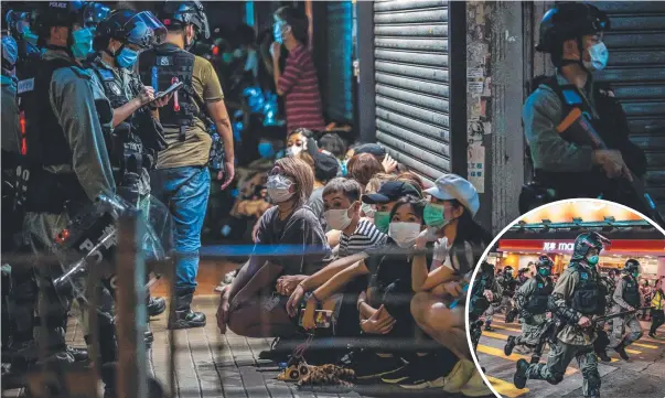  ?? Pictures: AFP, Getty Images ?? Police detain a group of people during a pro-democracy protest in Hong Kong calling for the city’s independen­ce, and, inset, officers wearing protective masks charge on a street during a demonstrat­ion in the Mong Kok district.