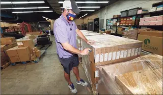  ?? David Zalubowski / Associated Press ?? Jason Rand cuts open the shrink wrap around a pallet of Lenovo Chromebook laptops as they sit in a Denver Public Schools warehouse after arriving Friday. Schools across the U.S. are facing shortages and long delays in getting laptops and other equipment needed for online learning.