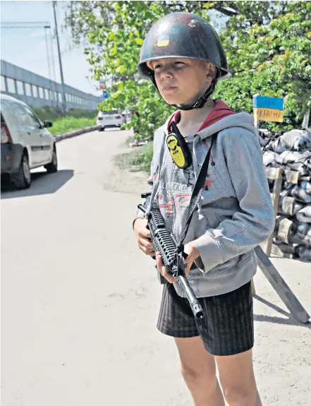  ?? ?? Right, Ukrainian children play territoria­l defence fighters at a fake “checkpoint” in the village of Stoyanka, in the Kyiv region