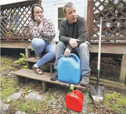  ?? ROBERT F. BUKATY/AP ?? Lucinda Tyler and Aaron Raymo sit outside their home with fuel containers they use to fill their heating oil tank at their home, Wednesday, in Jay, Maine. The couple shopped around for the best prices and bought heating oil 5 gallons at a time throughout the summer whenever they had any extra money.