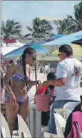  ??  ?? Una turista del “Carnival Fantasy” se dispone a ocupar una mesa en la soleada playa de Progreso. A la izquierda, otros pasajeros de crucero al cruzar la avenida del malecón