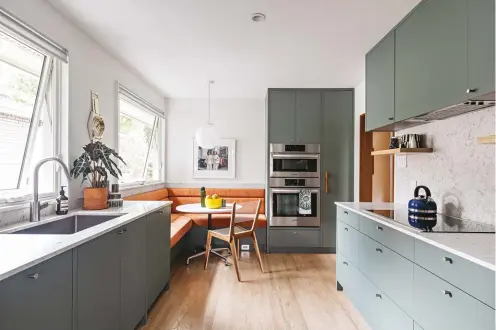  ??  ?? ABOVE Viridian painted MDF cabinetry meets quartz countertop­s and the velvet upholstery of the banquette in the ’60s-esque kitchen. Progress Lighting pendant; Eames table from Filter; Jacques Guillon Cord Chair.