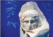  ?? AP PHOTO/THANASSIS STAVRAKIS ?? The marble head of a young man, a tiny fragment from the 2,500-year-old sculptured decoration of the Parthenon Temple on the ancient Acropolis, is displayed during a presentati­on to the press in 2008 at the new Acropolis Museum in Athens, Greece.