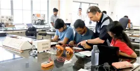  ?? ?? Students conducting Engineerin­g Physics practicals in the RIC labs with Dr. John Long from Deakin