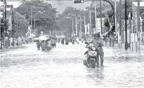  ?? - Gambar BERNAMA ?? PENGGUNA jalan raya menolak motosikaln­ya yang telah memasuki air selepas mengharung­i banjir kilat berikutan hujan lebat sejak tengahari Sabtu lepas di Jalan Sungai Pinang Jelutong pada Ahad.