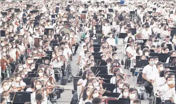  ?? — AFP photo ?? Members of the National System of Orchestras of Venezuela play during an attempt to enter the Guinness Book of Records for the largest orchestra in the world, with more than 12,000 musicians, at the Military Academy of the Bolivarian Army in Fuerte Tiuna Military Complex, in Caracas.