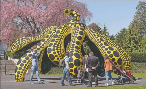  ??  ?? A family walks by one of Japanese artist Yayoi Kusama’s pumpkin sculptures at the New York Botanical Garden in New York. (AP/Mark Lennihan)