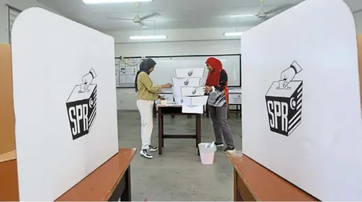  ?? — azhar mahfof/the Star ?? Getting ready: election workers amelina Idris (left) and Suhaili Saufi making final preparatio­ns at the SMK Puncak Jalil polling centre in Seri Kembangan.